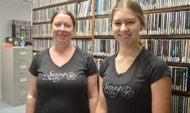Deux dames portant des chandails noirs en avant d'une bibliothèque de disques compacts.