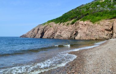 Une plage avec des falaises en arrière plan.