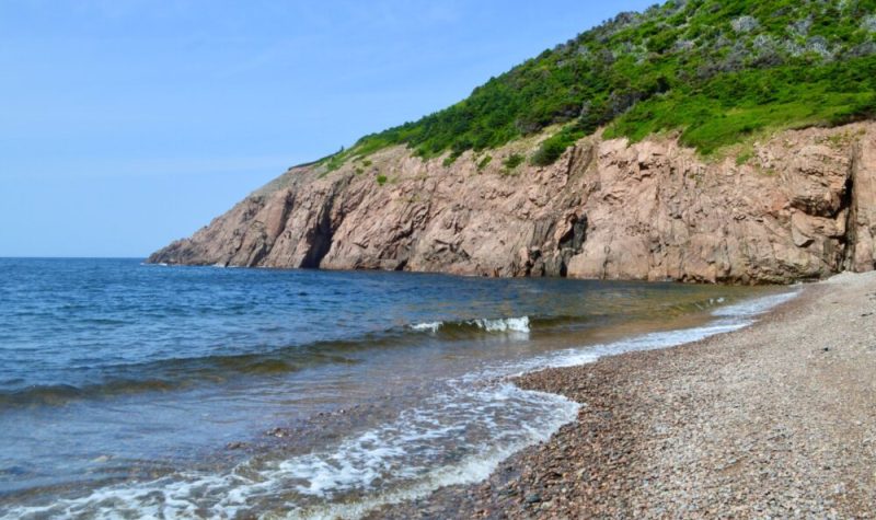 Une plage avec des falaises en arrière plan.