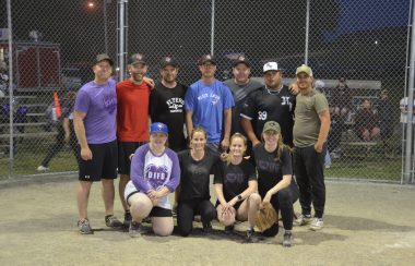 A softball team poses in front of home plate after wining a tournament.