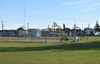 Une cour d'école avec un terrain de basketball et des autobus scolaires jaunes en arrière.