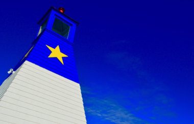 Phare avec étoile jaune contre un ciel bleu.