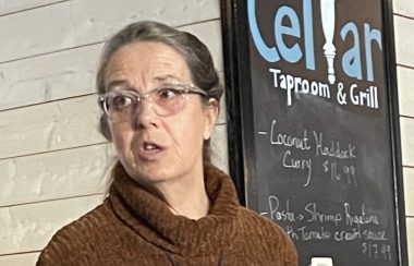 Mayor Darlene Norman speaks at an event in front of a chalkboard sign for the Cellar Tap Room and Grill.