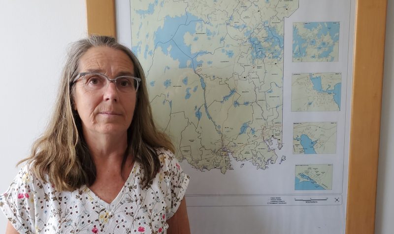 A woman stands in front of a map of Queens County
