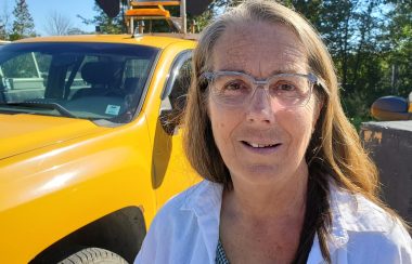 A woman stands in front of a pick up truck