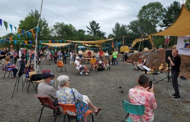 A large crowd gathered in construction site listens to a person speak