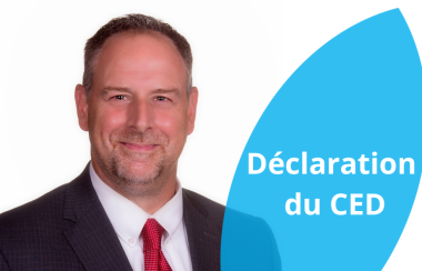 Michel Côté, le président du CED pose en costume sombre et cravate rouge sur fond blanc