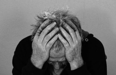 Un homme qui se tient la tête entre les mains en noir et blanc