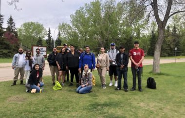 A group of students gathers for a picture outside in a park on an overcast day.