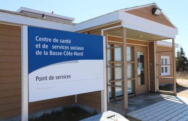 Un panneau mentionnant un point de service du CISSS de la Côte-Nord aux côtés de l'entrée d'un petit bâtiment d'un étage.