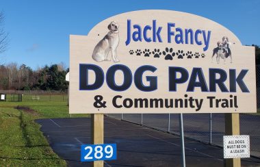 A dog park sign in front of a field