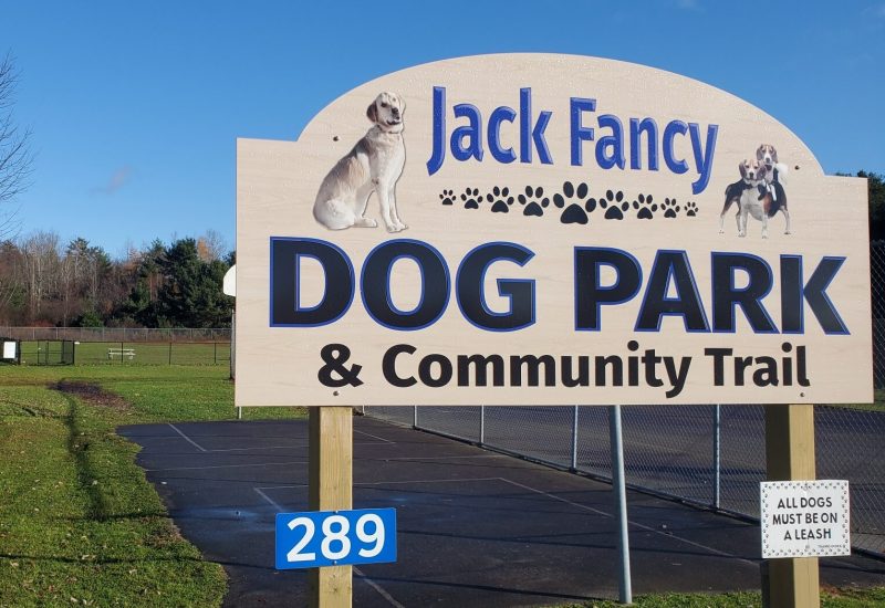 A dog park sign in front of a field