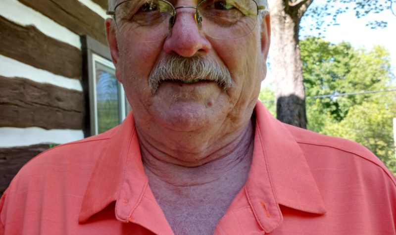 An outdoor selfie of Doug Rousselle, wearing glasses and an orange golf shirt.