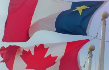Les drapeaux acadien et canadien flottant au vent