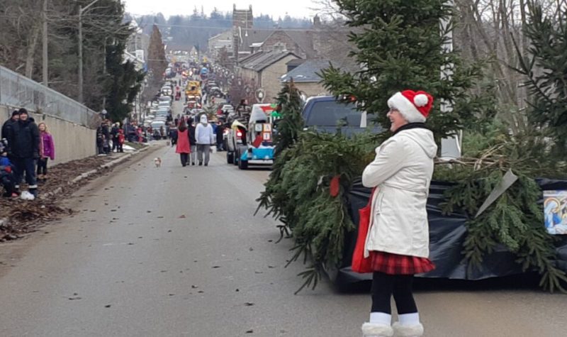 A photo of someone dressed as Santas behind a float of pine trees in a Santa Claus parade in Fergus in 2018.