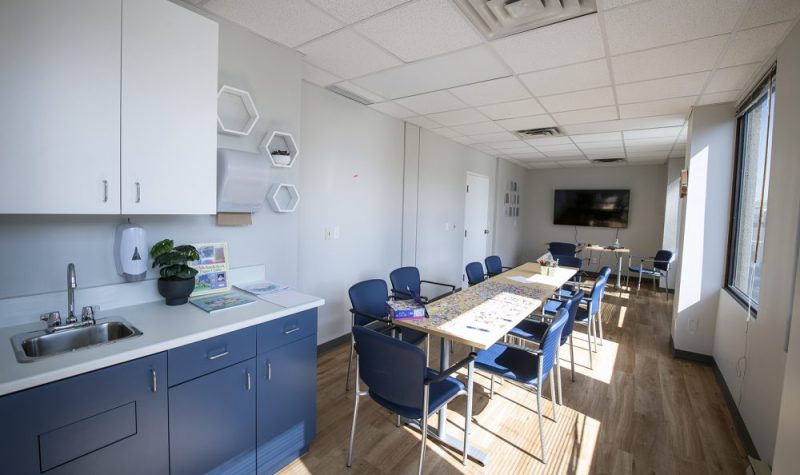 A kitchen and dining room accented with white and blue. There is a long table with chairs.