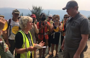 A settler elder confronting an RCMP officer , with media looking on