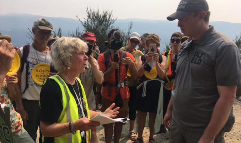A settler elder confronting an RCMP officer , with media looking on
