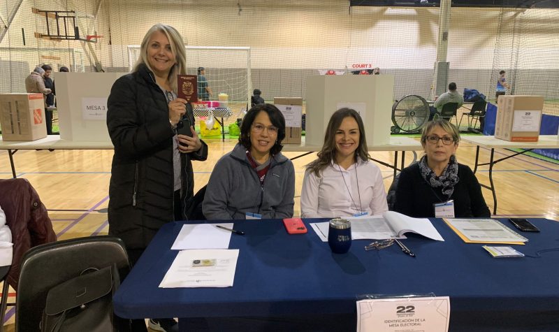 Personas sentadas en una mesa de votación.