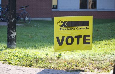 Une pancarte jaune d'élections Canada. Il est écrit «VOTE» au centre.