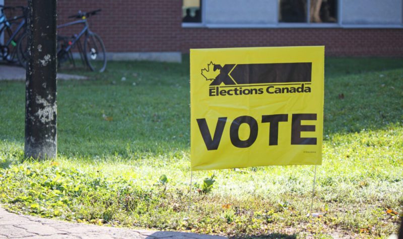 Une pancarte jaune d'élections Canada. Il est écrit «VOTE» au centre.
