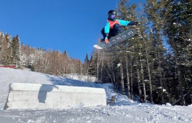 Une jeune fille faisant un grab en snowboard. Paysage d'hiver