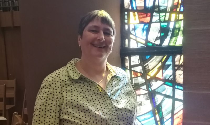 Woman standing in front of stained glass window.