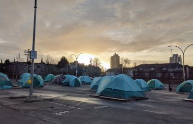 Numerous blue tents are seen in downtown Victoria at sundown