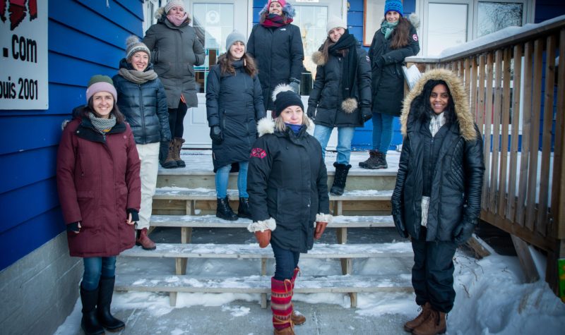 Photo de groupe hivernale de neuf femmes, l'une d'entre elle étant au centre, en évidence.