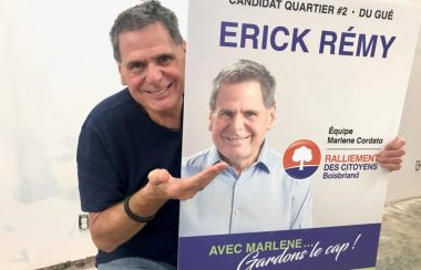 Érick Rémy tenant une affiche de sa campagne