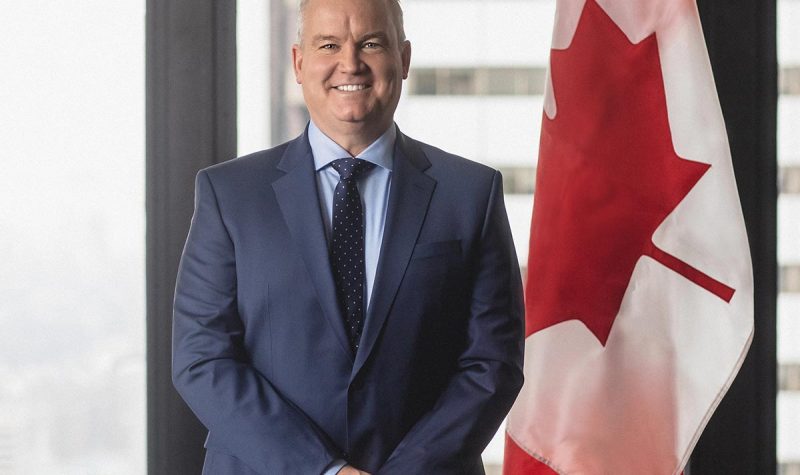 A man stands beside a Canadian flag