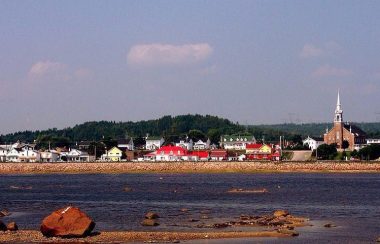 Vue de la municipalité avec un ciel dégagé et le fleuve à l’avant.