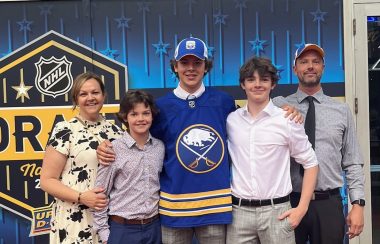 Ethan Miedema and family pose for a picture at the NHL draft. There is a blue background behind the five people.