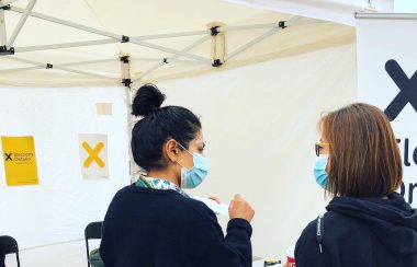 Dos personas paradas frente a una mesa de votación | Foto: Elections Ontario