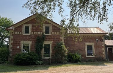 A sunny sky sits behind a red brick farmhouse on Gartshore Street in Fergus.