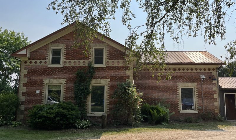 A sunny sky sits behind a red brick farmhouse on Gartshore Street in Fergus.