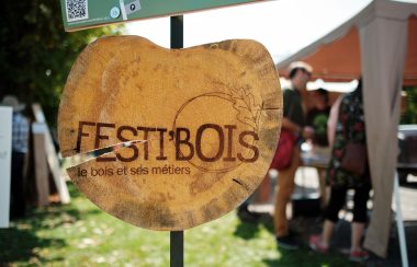 The sign for Festi'Bois. It is a round piece of wood with Festi'Bois - le bois et ses métiers written on it.