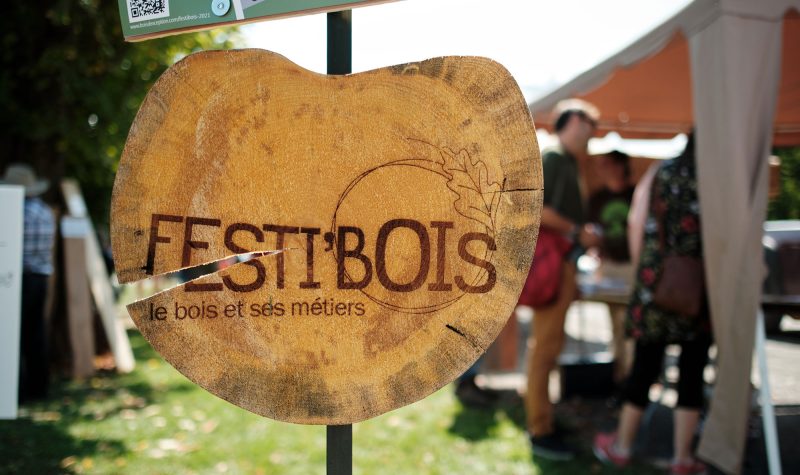 The sign for Festi'Bois. It is a round piece of wood with Festi'Bois - le bois et ses métiers written on it.