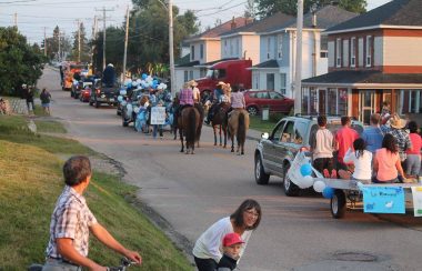 Des gens dans une parade de rue avec des voitures et des chevaux