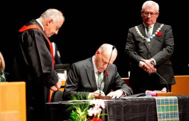 A photo of Councilor Dave Loewen signing a document next to Former Mayor Braun