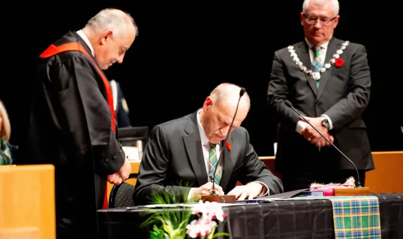 A photo of Councilor Dave Loewen signing a document next to Former Mayor Braun