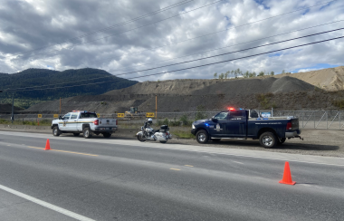 One white DFO truck, one dark blue conservation truck, and one RCMP motorcycle parked on the side of the road.