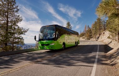 A bus travels through a road in the mountains.