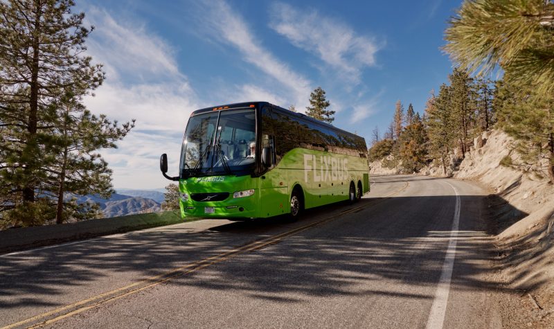 A bus travels through a road in the mountains.