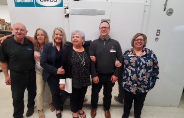 A group of people standing in front of a walk-in freezer