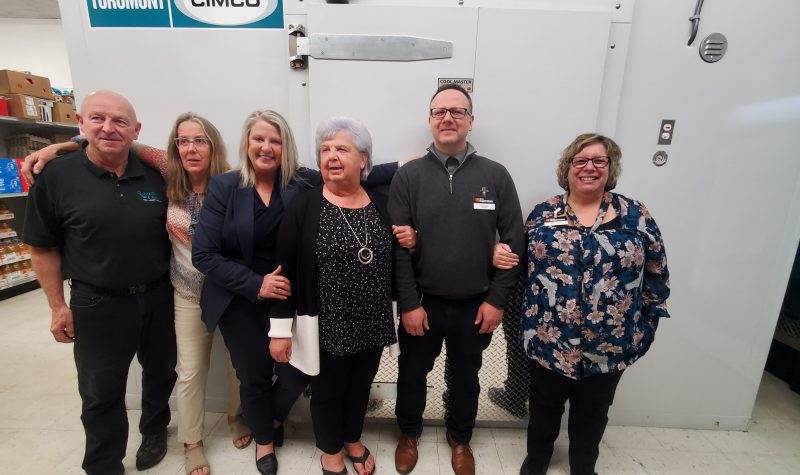 A group of people standing in front of a walk-in freezer