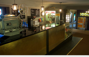 A concession table with a film projector and cash register in a half-lit room.