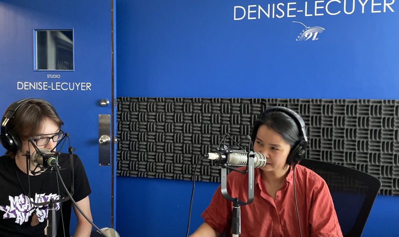 Phi-Vân Nguyen à droite, lors de notre entrevue et derrière se trouve un mur bleu sur lequel est écrit Studio Denise-Lécuyer.