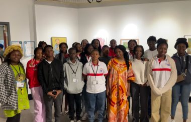 Les 18 élèves de la côte d'ivoire et leur professeur à l'extrême gauche, posant devant des œuvres d'art au centre culturel franco-manitobaine.