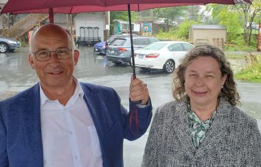 A man and a woman stand under an umbrella in the rain